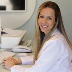 dra danuza dias mulher loira sentada com os braços sobre a mesa olhando para o lado e sorrindoDra. Danuza Dias Alves