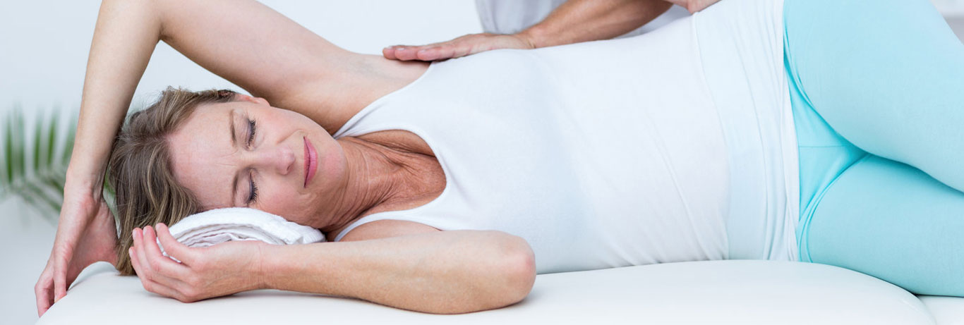 mulher deitada de lado recebe massagem nas costas