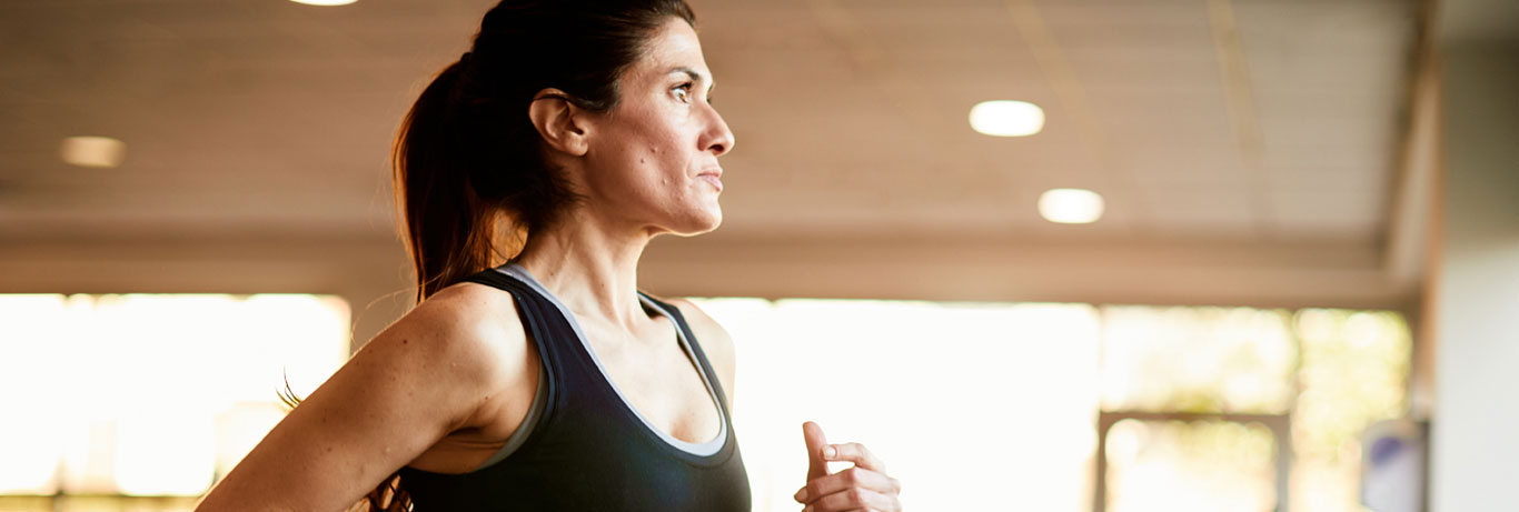 mulher correndo em esteira na academia