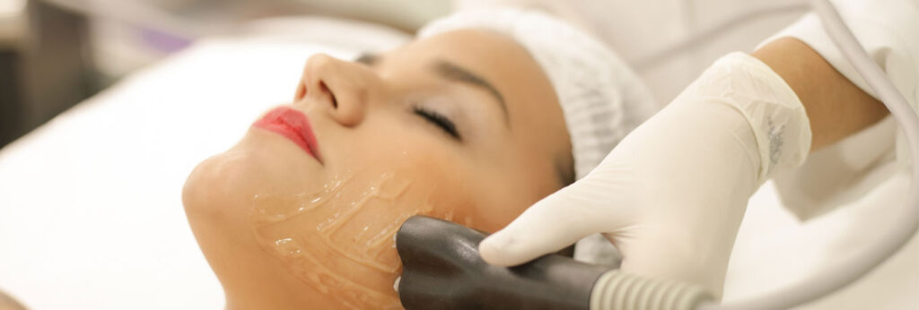 mulher deitada de olhos fechados com gel no rosto recebe tratamento de radiofrequência para flacidez facial