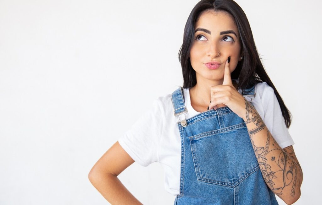 Fotografia de uma mulher, morena, com o braço esquerdo tatuado pensando em depilação a laser.