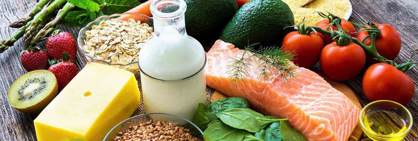 diferentes grupos de alimentos como carne, legumes, verdura, frutas, leite, oleaginosas sobre a mesa