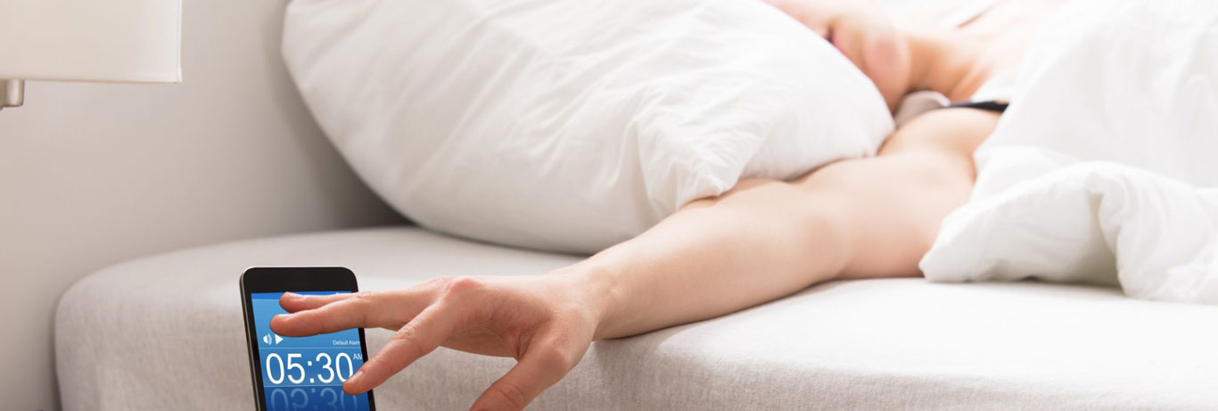 mulher deitada desliga o despertador sem acordar