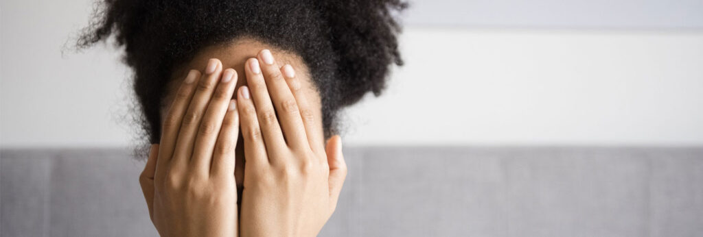 mulher com as mãos no rosto tapa o narizz