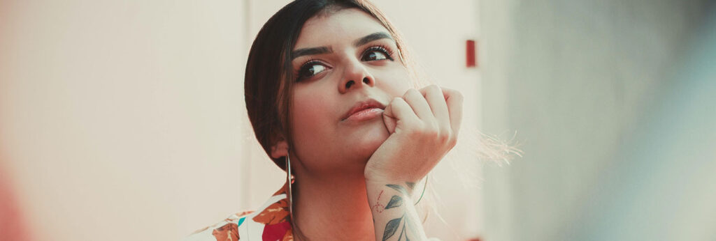 mulher com mao no queixo e tatuagem no pulso pensa onde remover tatuagem em sao paulo