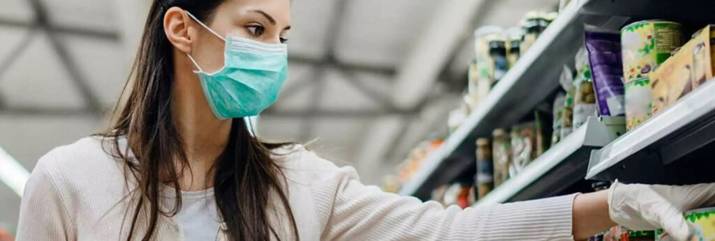 mulher de luva e máscara para se proteger do coronavíruas faz compras no supermercado