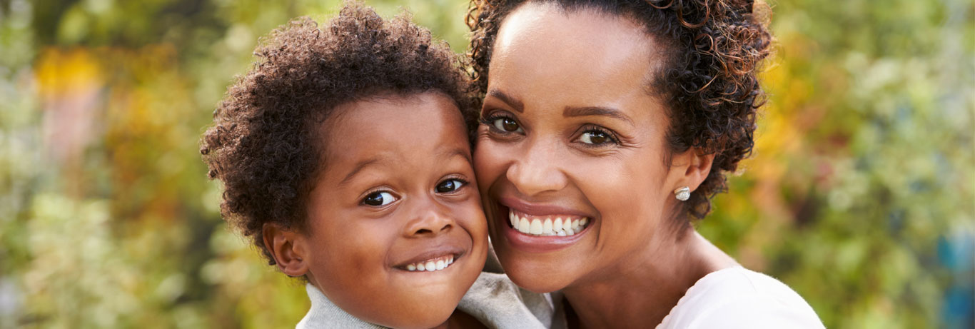 mãe feliz após a ciruriga plástica mommy makeover com o rosto grudado no filho pequeno sorrindo os dois olhando para câmera