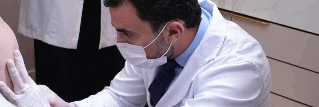 médico abaixado realizando tratamento da celulite com goldincision descolando as fibroses da paciente em pé