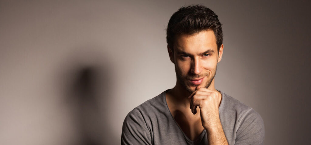 homem branco com barba e mão no queixo com visual harmonico após ter feito preenchimento facial masculino